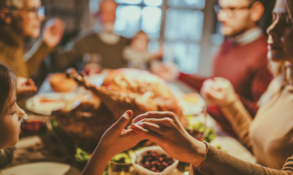 Family praying at a dinner table